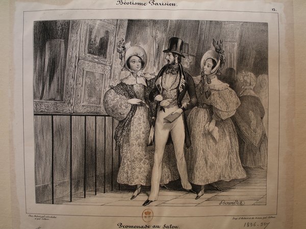 Historical engraving depicting a scene at an art exhibition during the July Monarchy. Two women and a man, all in period attire with hats and top hats, are viewing paintings. The man has facial hair, and the surroundings suggest a salon setting, implied to be the Salon Livret.