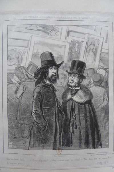 Black and white illustration of a crowded salon scene featuring men and women. Two men in the foreground wear top hats; one has long hair and a pince-nez, while the other displays bourgeois attire and facial hair. Background shows other individuals in varied outfits and hats, with paintings hung around them, capturing a typical salon setting during the July Monarchy.